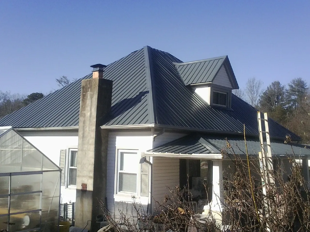 Dark blue standing seam metal roof on a white farmhouse with dormer — Slate & Tile Roof Repair by Roofing Brothers in Carrolls
