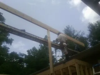 Carpenter setting a ridge beam over a new addition frame — Ice Dam Removal by Roofing Brothers in Carrolls