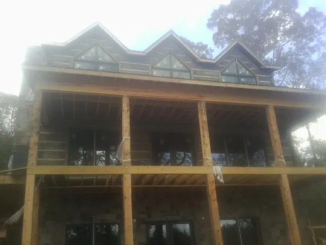 Dormers and porch framing on a large log home under construction — Roof Coating work by our crew in Carrolls