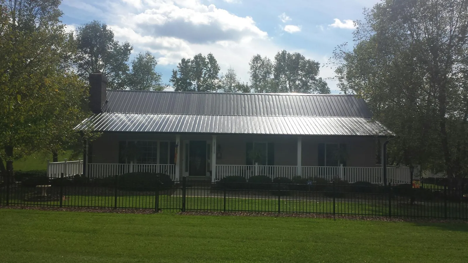 Gray metal roof on a brick ranch with a full width front porch in Carrolls