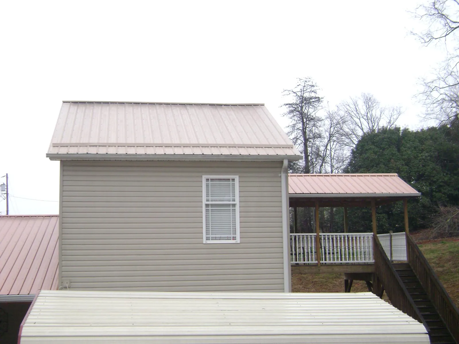 Tan metal roofs on a two story addition and attached porch, from a Roof Replacement job in Carrolls