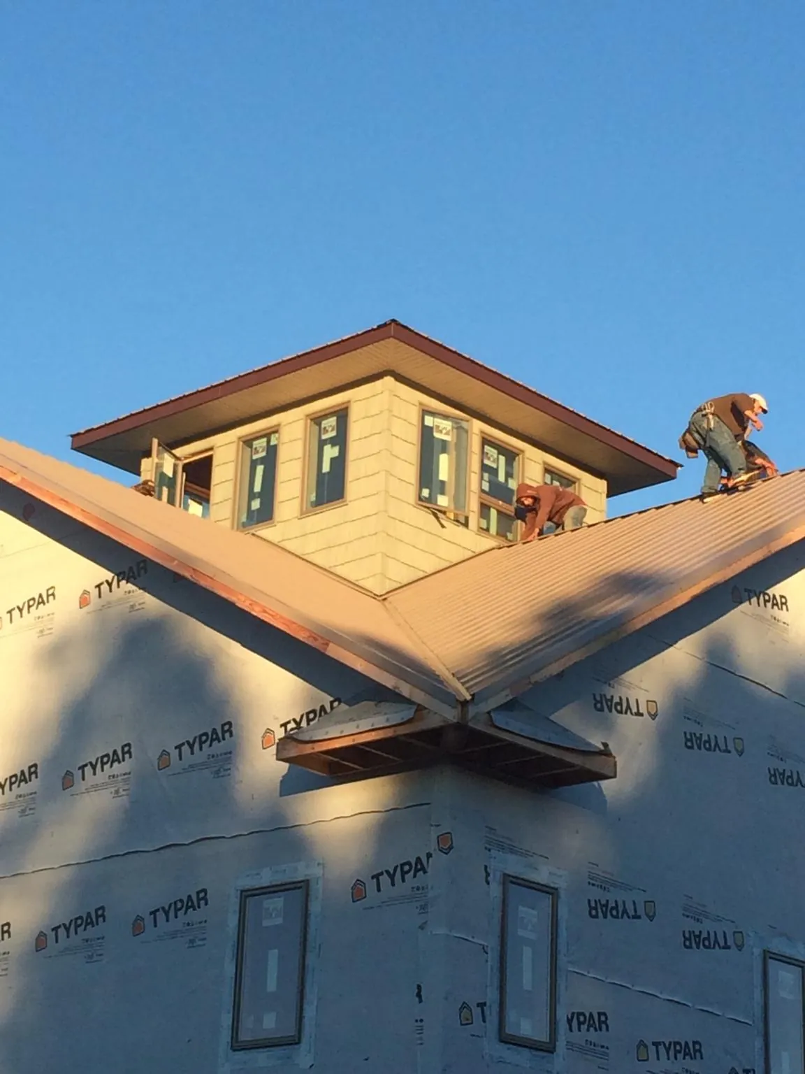 Roofers working around a rooftop cupola on a new metal roof at sunset — Roof Waterproofing in Carrolls by Roofing Brothers